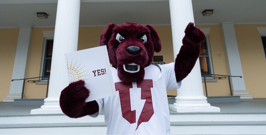 Charger standing in front of a building holding a folder that says YES!