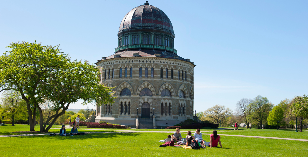 Students sitting on the grass in front of the Nott on a sunny day. 