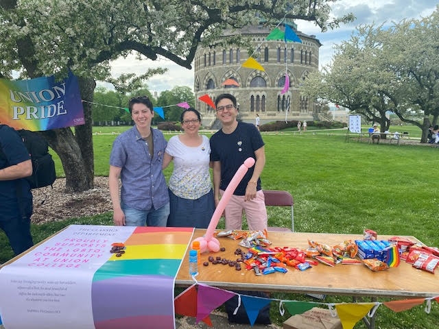 Union College Classics Professors Nick Winters, Stacie Raucci, and Tommaso Gazzarri, stand at a Union Pride table.