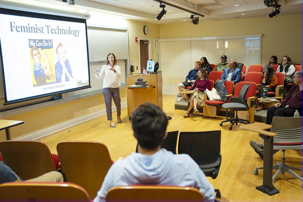 A professor gestures to a screen in the performance classroom at Karp Hall.