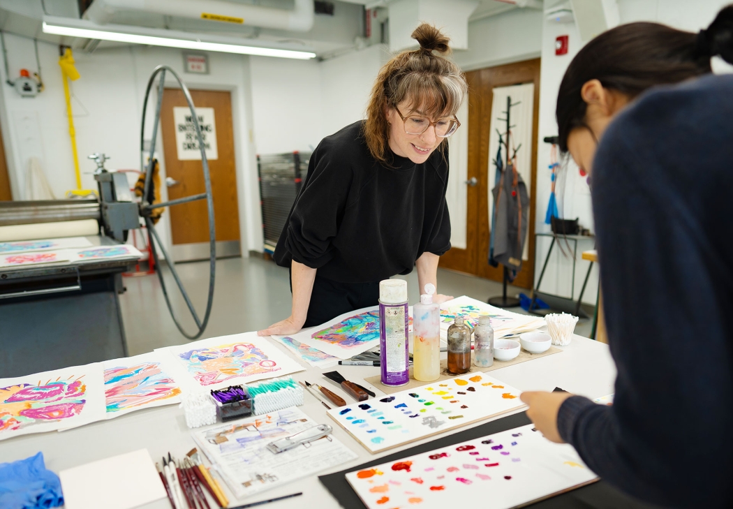 An instructor watches as student applies ink to her printmaking project