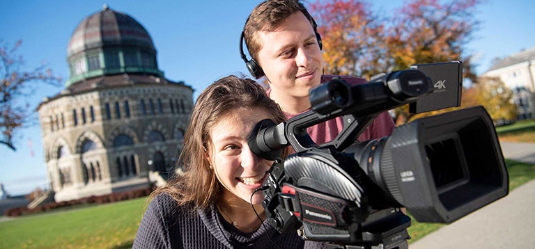 The Nott Memorial is in the background as two students operate a video camera