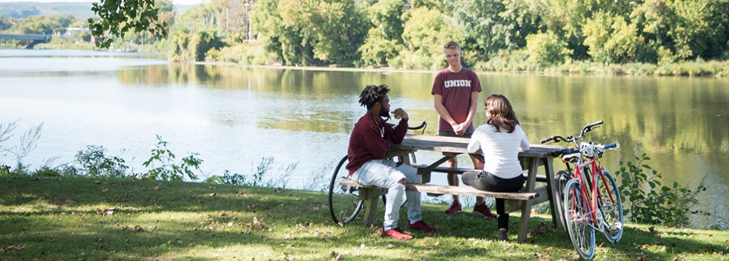 Staff and students having a chat by picnic table near the Mohawk River