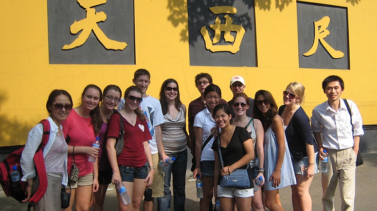 A group stands in front of a wall with Chinese writing