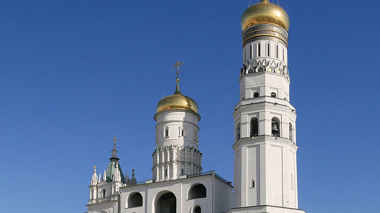 A Russian Orthodox church with golden domes, set against a vibrant blue sky.