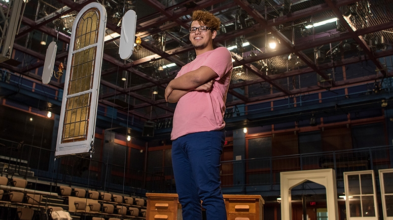 A student stands on set furniture in the Yulman Theater