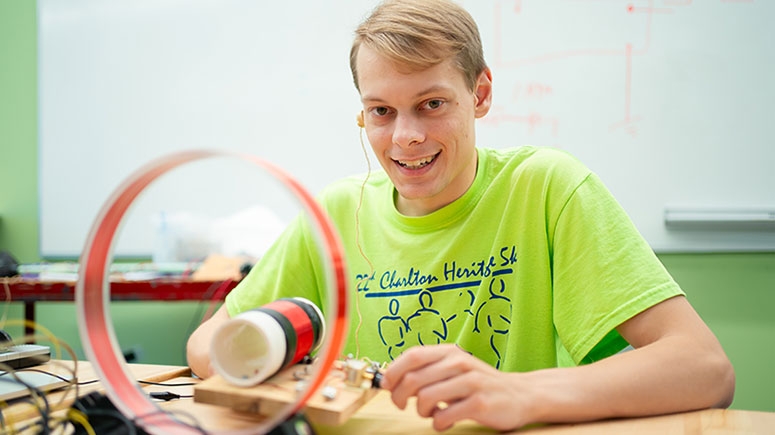 A student poses with his electrical generator that he constructed as part of a class project