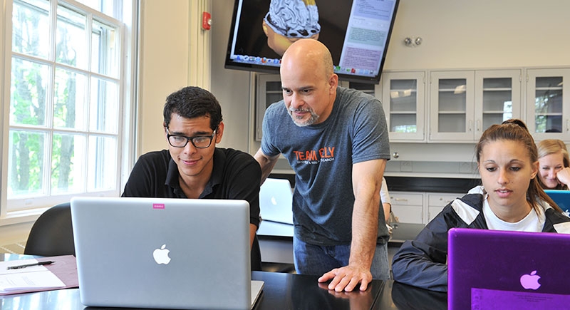  A professor and students are gathered around a computer screen in one of the neuroscience labs situated within Butterfield Hall.