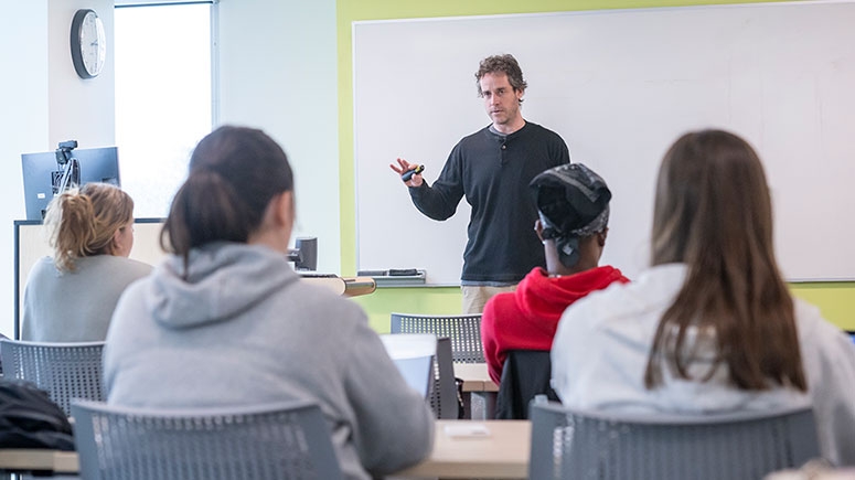 A psychology professor gestures as he speaks in front of the class