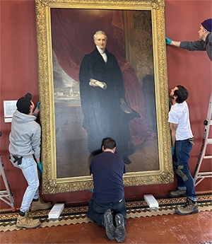 Workers carefully prepare to return a historic portrait of Eliphalet Nott, Union's longtime president, to its pictorial space at the back of the Nott Memorial. The painting had been removed in March 2022 to be restored at the Williamstown Art Conservation Center.