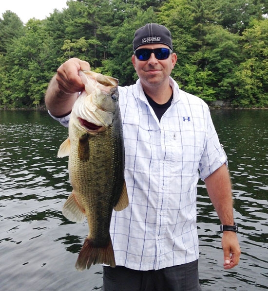 :Scott Rava shows off an eight-pound largemouth bass, the biggest one of this species he’s ever caught.