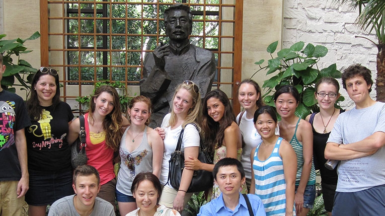 Students on a study abroad term in China stand in front of an ancient statue of Confucius, the famous philosopher.